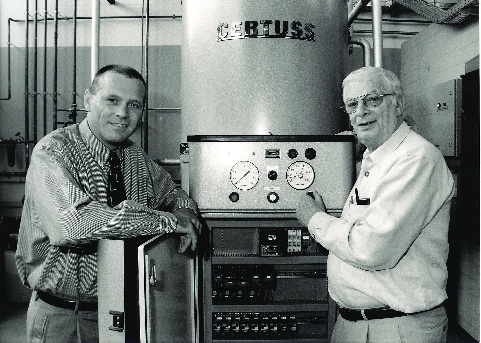 Schwarz/weiß Foto von Zwei Personen vor einem alten Dampfgenerator